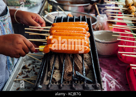 Einem Straßenhändler macht Gegrillte thailändische Würstchen am Spieß am Warorot Market, Chiang Mai, Thailand. Stockfoto