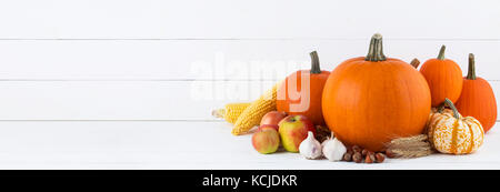 Herbst ernte noch leben mit Kürbissen, Weizenähren, Haselnüsse, Knoblauch, Zwiebel, Apfel und Mais auf weißem Holz- Hintergrund Stockfoto