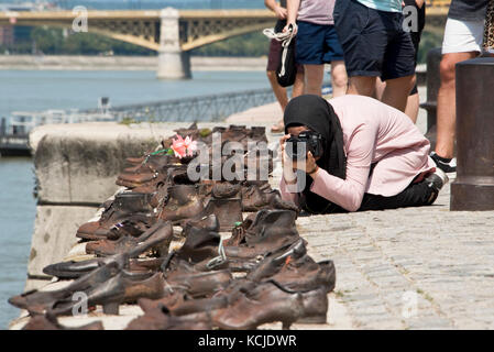 Die Schuhe am Donauufer Denkmal in Budapest an einem sonnigen Tag mit einem Touristen fotografieren. Stockfoto