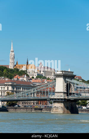 Ein Blick auf die Széchenyi Kettenbrücke über die Donau in Budapest mit der Fischerbastei und Matthias Kirche im Hintergrund. Stockfoto