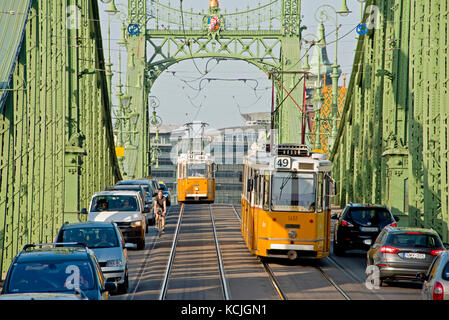 Die ganz CSMG-Straßenbahn in Budapest überquert die Freiheitsbrücke an einem sonnigen Tag mit blauem Himmel. Stockfoto