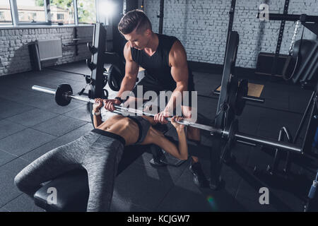 Trainer helfen Frau weightlifting Stockfoto