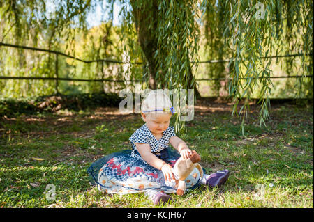 Baby Mädchen sitzen auf dem Gras und spielen mit ihren Teddybären Stockfoto