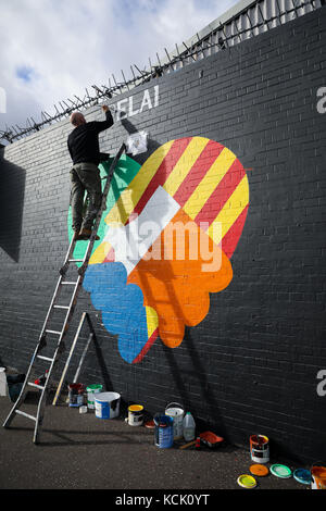 Belfast, Nordirien. Oktober 2017. Zwei irische republikanische Kunstaktivits greifen auf eine Mauer an der „International Wall/Divis Street“ zurück, um die Indepedenzbewegung in Katalonien, in Belfast, Nordirien, am 5. Oktober 2017 zu unterstützen. Die Briefe lauten: "Irland steht mit Katalonien". Quelle: Christian Charisius/dpa/Alamy Live News Stockfoto