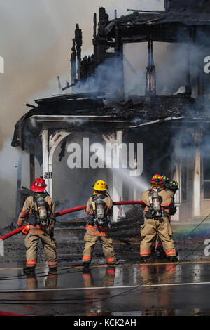 Feuerwehrleute aus mehrere benachbarte Städte in der Schlacht eine große Haus Feuer unbekannter Herkunft auf der Hauptstraße in der Stadt. Es wurden keine Personen verletzt oder in dieser Tragödie in Lissabon, NH, USA getötet. Stockfoto