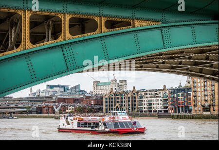 Gewölbte Abschnitt von Southwark Bridge auf Bankside, mit einem langen Bootsfahrt auf der Themse und Riverside Gebäude, London, England, UK. Stockfoto