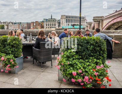 Eine Gruppe von Menschen sitzen in Getränke außerhalb Doggett's Pub, direkt neben der viktorianischen Ära Blackfriars Bridge, South Bank, London, England, UK. Stockfoto