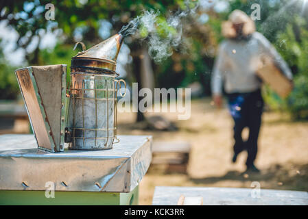 Imker Kiffen stehend auf die Bienenstöcke Stockfoto