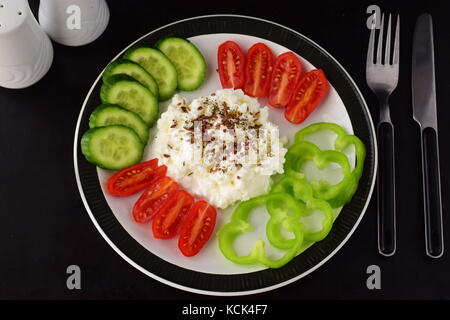 Einfaches Frühstück mit Paprika, Tomaten, Gurken mit Quark und Leinsamen auf einem Schild auf einem dunklen Hintergrund Gesunde Ernährung Gesunde Ernährung Konzept. Stockfoto