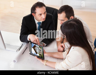 Glückliches junges Paar diskutiert mit Berater im Büro Stockfoto