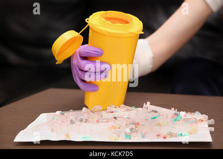 Medizinische Abfälle mit gebrauchten Spritzen und Nadeln in wiederverwendbare Behälter Stockfoto