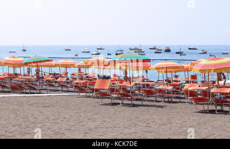 Positano, Italien - Juni 28; sand Strand an der Küste von Amalfi mit orangen Sonnenschirme und Touristen in Positano, Italien - Juni 28, 2014; busy mediterrane Sand. Stockfoto
