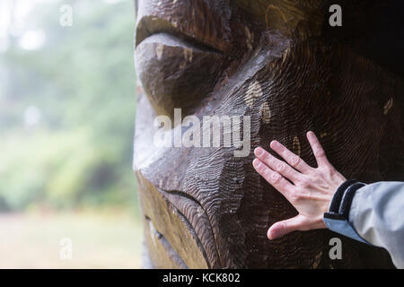 Ein nasser Gedenkstein enthüllt seine strukturellen Schichten einem Besucher im Friendly Cove, Yuquot, Westküste Vancouver Island, British Columbia, Kanada Stockfoto