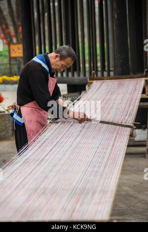 Guilin, China - Januar 29, 2013: Ein alter Mann weben ein langes Stück der traditionellen Tuch in einer Minderheit Dorf bei Yangshuo, China. - Weaver in der Minderheit Stockfoto