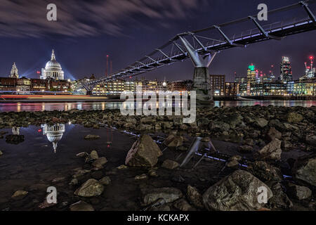 Skyline von London, Thames Bank unter St Paul's bei Ebbe, benetzt Felsen und Reflexionen, die Millennium Bridge bei Nacht Stockfoto