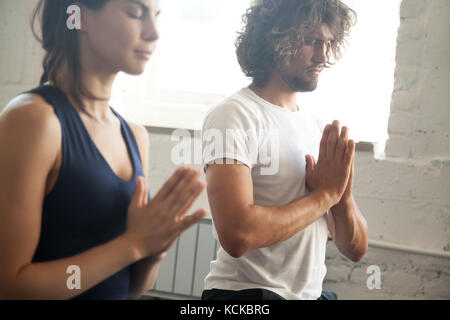 Gruppe von jungen sportlichen Menschen, namaste Geste, Mann und Frau, meditieren, Yoga Unterricht mit Kursleiter, Trainieren, Hallenbad in der Nähe der im Stockfoto