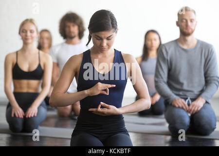 Gruppe junge sportliche Menschen üben Yoga Lektion mit Instructor, vajrasana Übung sitzen, Seiza darstellen, Arbeiten, Indoor, Studio. Wohlbefinden Stockfoto