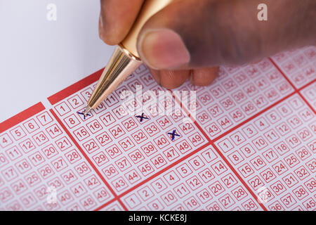 Nahaufnahme einer Person Kennzeichnung Nummer auf Lottery ticket mit Stift Stockfoto