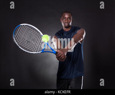 Porträt der jungen afrikanischen Mann spielt Tennis auf schwarzem Hintergrund Stockfoto