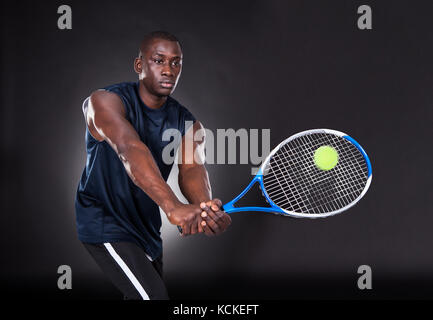 Porträt der jungen afrikanischen Mann spielt Tennis auf schwarzem Hintergrund Stockfoto