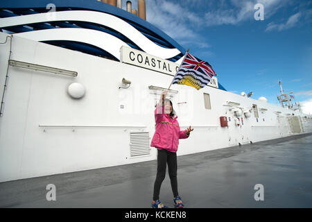 Mädchen winken British Columbia Flagge auf dem Coastal Inspiration von BC Ferries, Salish Sea, British Columbia, Kanada Stockfoto