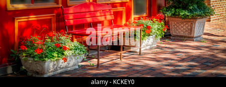 Eine bunte Sitzbank und Blumen auf der gepflasterten Gehsteigen im nördlichen Virginia. Stockfoto