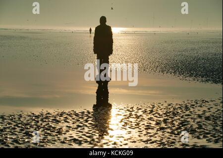 Silouhette von Sir Antony Gormley, einem anderen Ort Skulpturen am Crosby Beach Stockfoto