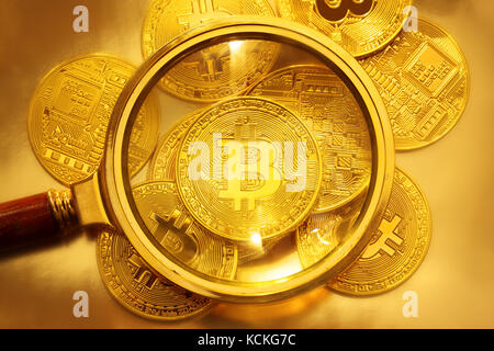 Blick durch ein Vergrößerungsglas auf neue goldene Bitcoin Stockfoto