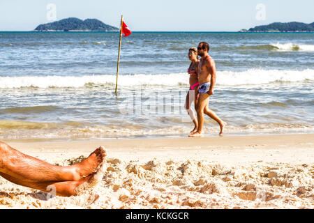 Gestreckte Beine eines Mannes auf dem Sand am Acores Beach. Florianopolis, Santa Catarina, Brasilien. Stockfoto