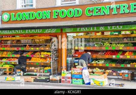 Obst- und Gemüsehändler tägliches Ritual Lagerung von Obst und Gemüse Regale außerhalb thier Shop auf der Römerstraße in Bow in London, England. Stockfoto