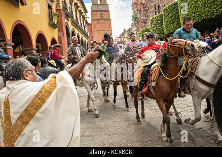 Mexikanischen Cowboys sind mit Weihwasser besprengt durch katholische Priester den Segen ihrer Wallfahrt während des Festivals von St. Michael in San Miguel de Allende, Mexiko. Stockfoto