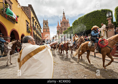 Mexikanischen Cowboys sind mit Weihwasser besprengt durch katholische Priester den Segen ihrer Wallfahrt während des Festivals von St. Michael in San Miguel de Allende, Mexiko. Stockfoto