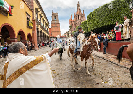 Mexikanischen Cowboys sind mit Weihwasser besprengt durch katholische Priester den Segen ihrer Wallfahrt während des Festivals von St. Michael in San Miguel de Allende, Mexiko. Stockfoto