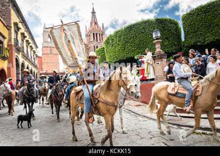 Mexikanischen Cowboys sind mit Weihwasser besprengt durch katholische Priester den Segen ihrer Wallfahrt während des Festivals von St. Michael in San Miguel de Allende, Mexiko. Stockfoto