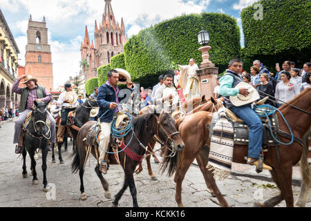 Mexikanischen Cowboys sind mit Weihwasser besprengt durch katholische Priester den Segen ihrer Wallfahrt während des Festivals von St. Michael in San Miguel de Allende, Mexiko. Stockfoto