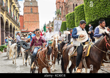 Mexikanischen Cowboys sind mit Weihwasser besprengt durch katholische Priester den Segen ihrer Wallfahrt während des Festivals von St. Michael in San Miguel de Allende, Mexiko. Stockfoto