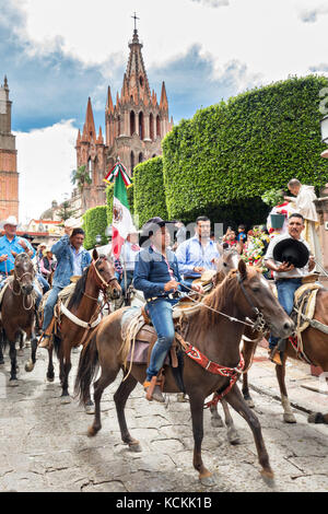 Mexikanischen Cowboys sind mit Weihwasser besprengt durch katholische Priester den Segen ihrer Wallfahrt während des Festivals von St. Michael in San Miguel de Allende, Mexiko. Stockfoto