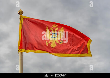 Die Flagge von Montenegro im Wind flattern gegen einen bewölkten Himmel Hintergrund. Stockfoto