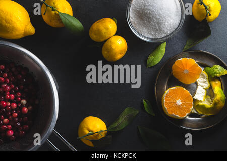 Rahmen der Mandarinen, Zitronen- und Preiselbeeren auf einem grauen Tisch horizontal Stockfoto