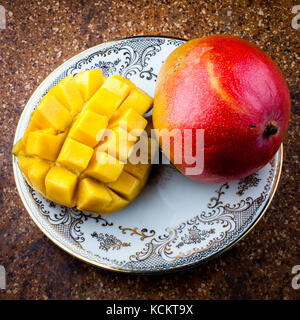Gewürfelte Mango wird hergestellt, indem man eine Frucht schneidet, den Stein entfernt und dann in der Schale in Würfel schneidet, die erst am Ende aus der Schale geschnitten werden Stockfoto
