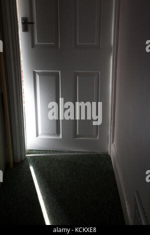 Welle von Sonnenlicht fällt auf den Boden durch die leicht geöffnete moderne B&Q Tür. Stockfoto