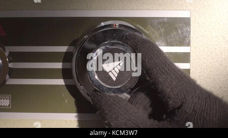 Männliche Hand stellt Gas auf Gasherd ein. Mit der Hand können Sie die Wassertemperatur an einem weißen Boiler einstellen. Es scheint sich in Richtung MAX zu drehen. Nahaufnahme eines Mannes, der das Zifferblatt einstellt. Stockfoto