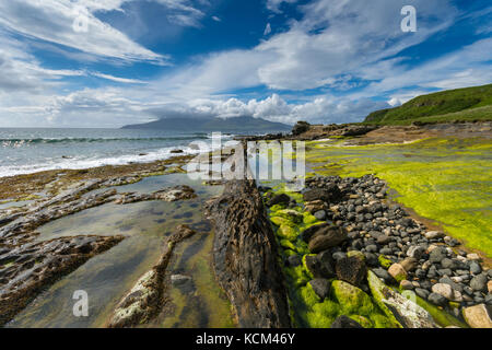 Basaltdeich Felsformationen am Strand an der Bucht von Laig, auf der Isle of Eigg, Schottland, Großbritannien. Dahinter ist die Isle of Rum. Stockfoto