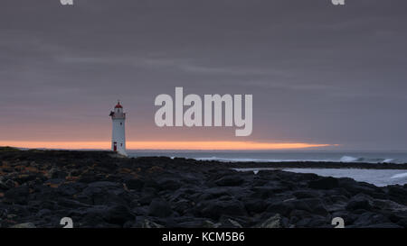 Port Fairy Leuchtturm bei Sonnenaufgang mit Felsen Stockfoto