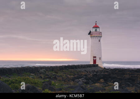 Port Fairy Leuchtturm bei Sonnenaufgang mit Felsen Stockfoto