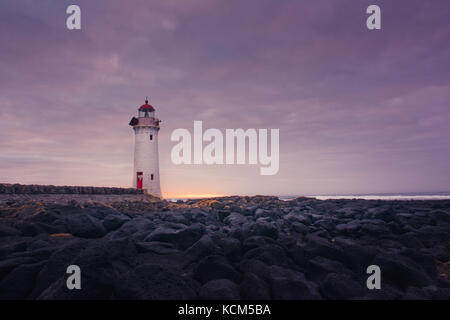 Port Fairy Leuchtturm bei Sonnenaufgang mit Felsen Stockfoto