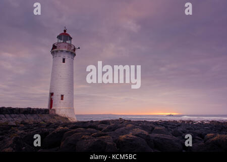 Port Fairy Leuchtturm bei Sonnenaufgang mit Felsen Stockfoto