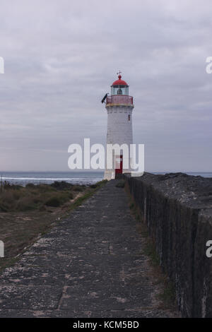 Port Fairy Leuchtturm bei Sonnenaufgang mit Felsen Stockfoto