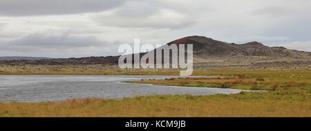Alte Lavafelder, grüne Wiese und Teich in Island. Stockfoto