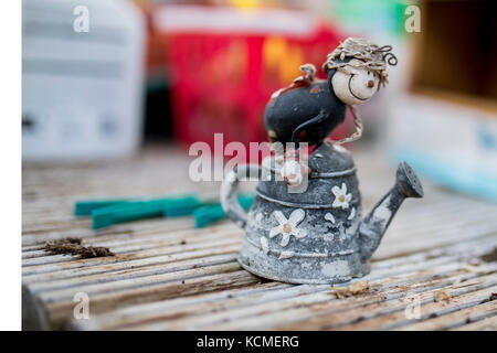 Schrullige ornamentalen Charakter reiten auf einem rustikalen Blume dekoriert Gießkanne in einer traditionellen englischen Potting Shed oder Green House Stockfoto